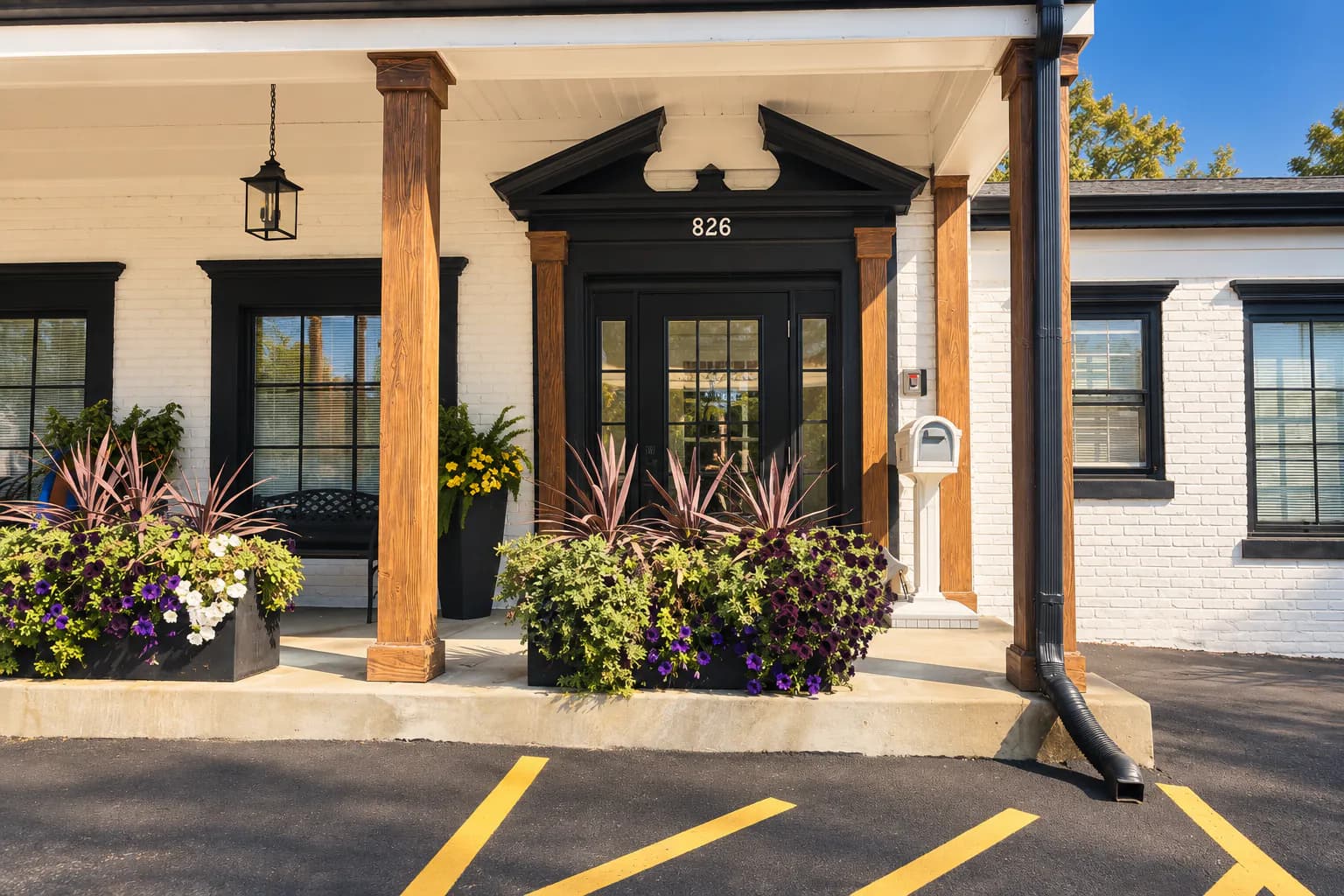Synthesised image: the white-brick entrance of the practice with wood columns, a black pediment over the door, the number 826 and planters of purple flowers.